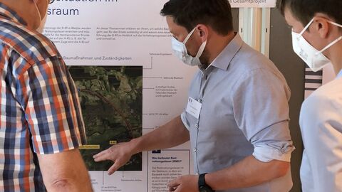 Personen erläutern Besuchern Informationen auf Infotafeln bei der Infomesse