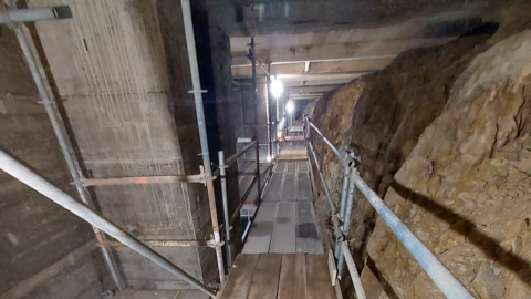 Hangstützwand, Ansicht von innen mit Laufgittern, Brettern und Handläufen aus Metall im inneren der Hangstützwand